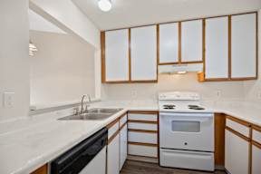 A kitchen with a white stove and white cabinets.