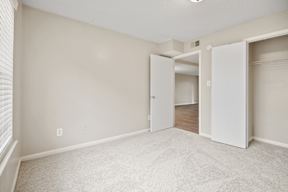 A room with white walls and carpeted floor with two open doors.