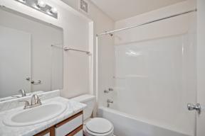 A white bathroom with a toilet, sink, and bathtub.