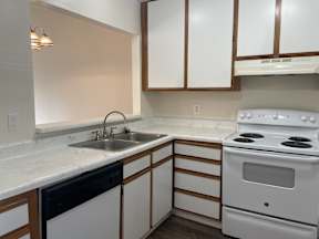 A kitchen with white appliances and wooden cabinets.