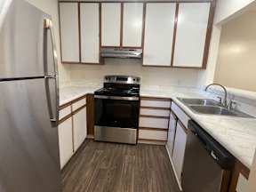 A kitchen with a stove, refrigerator, and cabinets.