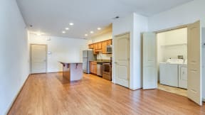 an empty living room and kitchen with wood floors and white walls