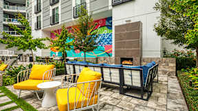 A patio with yellow chairs and a fireplace at Mosaic Summit Pointe in Chesapeake, VA, 23320