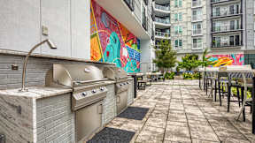 A patio with a grill and chairs is surrounded by a colorful mural at Mosaic Summit Pointe in VA, 23320