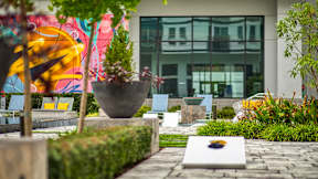 A modern building with a glass facade and a colorful mural on the wall at Mosaic Summit Pointe in Chesapeake, VA