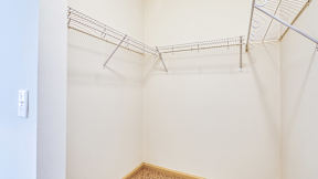 A white wall with a light switch and a wire shelf.
