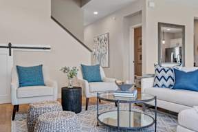 A living room with a white couch, a glass coffee table, and a painting on the wall.