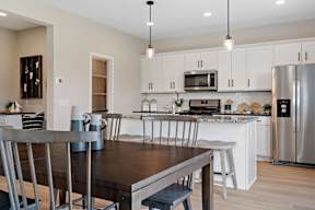 A modern kitchen with a wooden table and stainless steel appliances.
