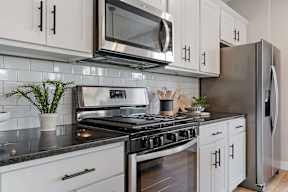 A kitchen with white cabinets and a black countertop.