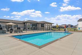 A large swimming pool in front of a building with a fence around it.