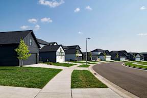 A row of houses with a tree and a sidewalk in front.