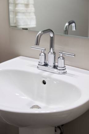 A white sink with a chrome faucet and a mirror above it.