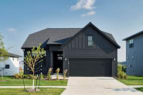 A modern house with a dark grey exterior and a large garage door.