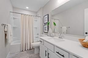 A white bathroom with a toilet, sink, and shower.