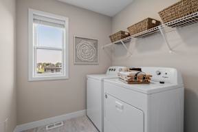 A laundry room with a washer and dryer, a window, and a picture on the wall.