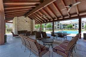 A patio with a table and chairs and a pool in the background.
