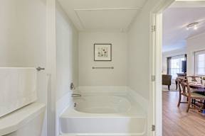 A white bathroom with a tub and a picture on the wall.