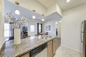 A kitchen with granite countertops and a vase of white flowers.