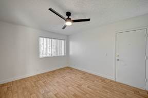 A room with a ceiling fan and wooden flooring.