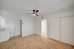 A room with a ceiling fan and wooden flooring.
