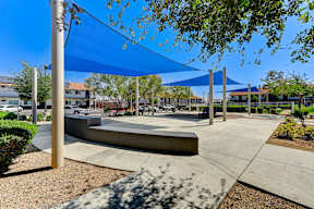 A playground with a blue canopy and a concrete structure.