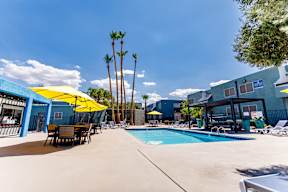 A pool area with a yellow umbrella and a blue building in the background.