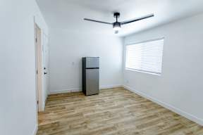A room with a ceiling fan and a refrigerator.