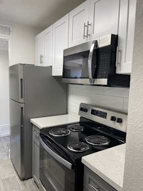 A kitchen with a stove, refrigerator, and microwave.