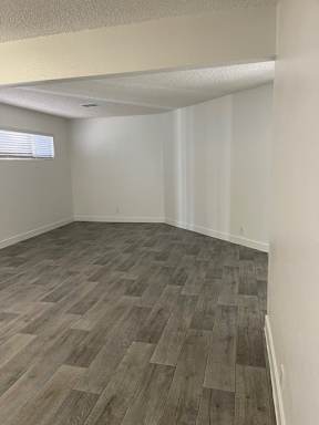 A room with wooden flooring and white walls.