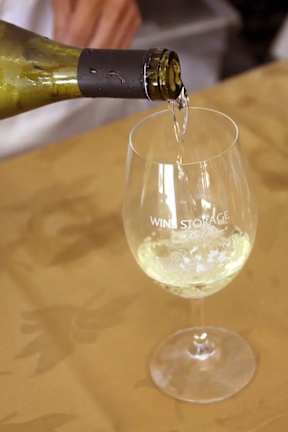 A bottle of wine is being poured into a wine glass.