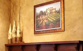 A painting of a street scene is hanging on a wall above a wooden shelf.