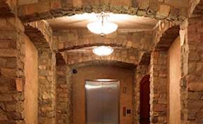 A stone archway leads to a door in a stone wall.