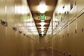 A long hallway with a green exit sign at the end.