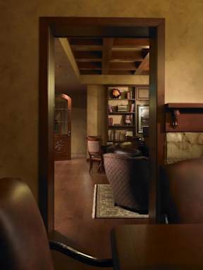 A room with a brown chair and a brown table with a mirror reflecting the room.