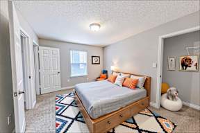 A bedroom with a bed, a rug, and a picture on the wall.