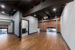 A room with a brick fireplace and wooden floors.