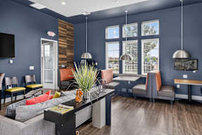 A modern living room with a grey couch, a black coffee table, and a flat screen TV mounted on the wall.