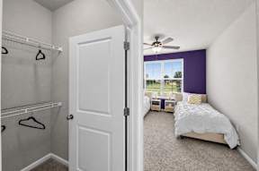 A bedroom with a white bed and a purple accent wall.