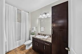 A bathroom with a white shower curtain and a brown door.