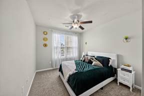A bedroom with a bed, nightstand, and window with curtains.