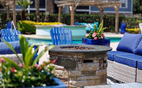 A patio with a fire pit and chairs.