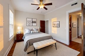 A bedroom with a bed, a bench, and pictures on the wall.
