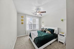 A bedroom with a bed, nightstand, and a ceiling fan.