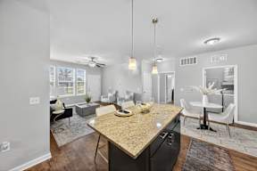A kitchen with a granite countertop and a dining area with a white table and chairs.