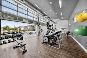 A gym with a variety of equipment including weights, a rowing machine, and a stationary bike.