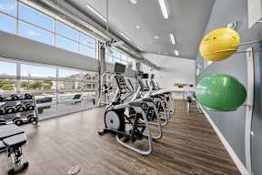 A gym with a row of treadmills and a green exercise ball.