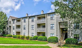A large apartment building with a green lawn in front.