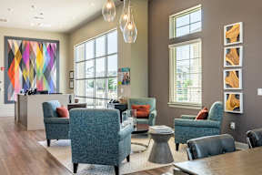 A room with a large painting and a group of chairs.