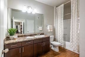 A bathroom with a brown vanity and a white toilet.