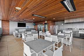 A modern kitchen and dining area with a wooden ceiling and white chairs.